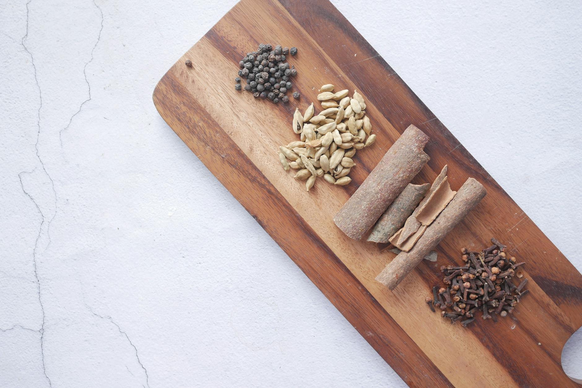 Przyprawy: kardamon, cynamon, goździki i pieprz na drewnianej desce