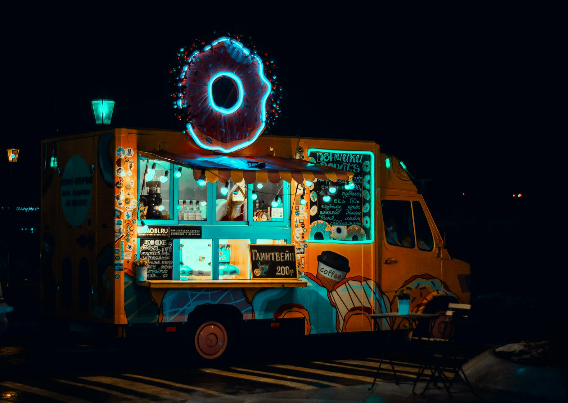 Nocny food truck z neonowym pączkiem serwujący przekąski
