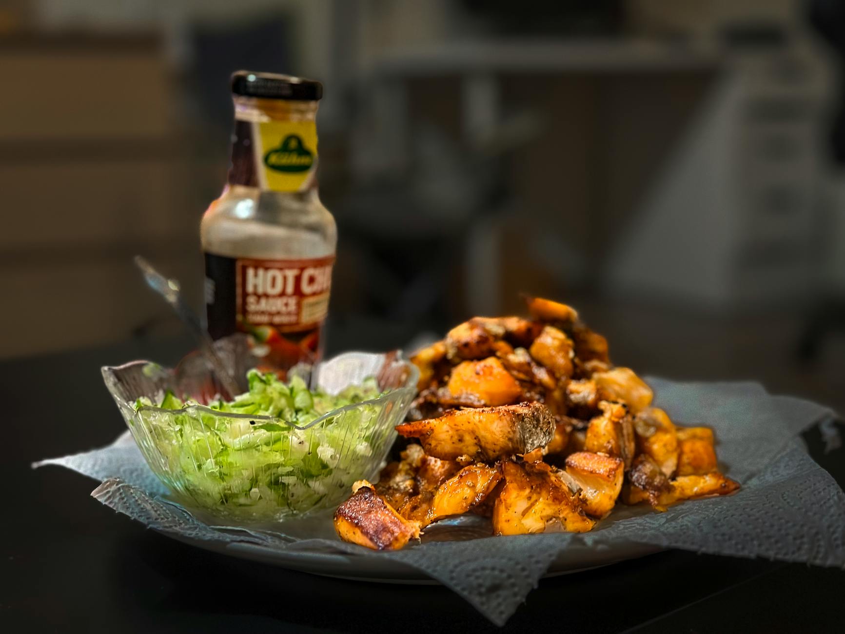 Pieczone ziemniaki z ostrym sosem i świeżą sałatą na talerzu