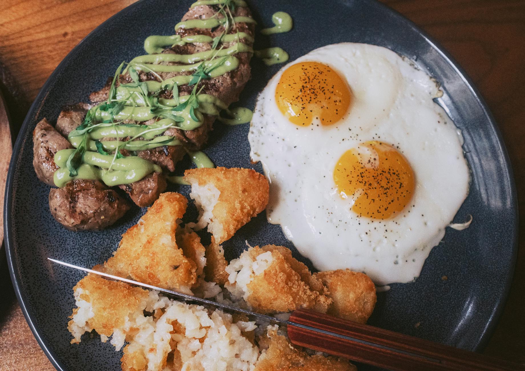 Stek z sosem, jajka sadzone i chrupiące placki ziemniaczane na talerzu
