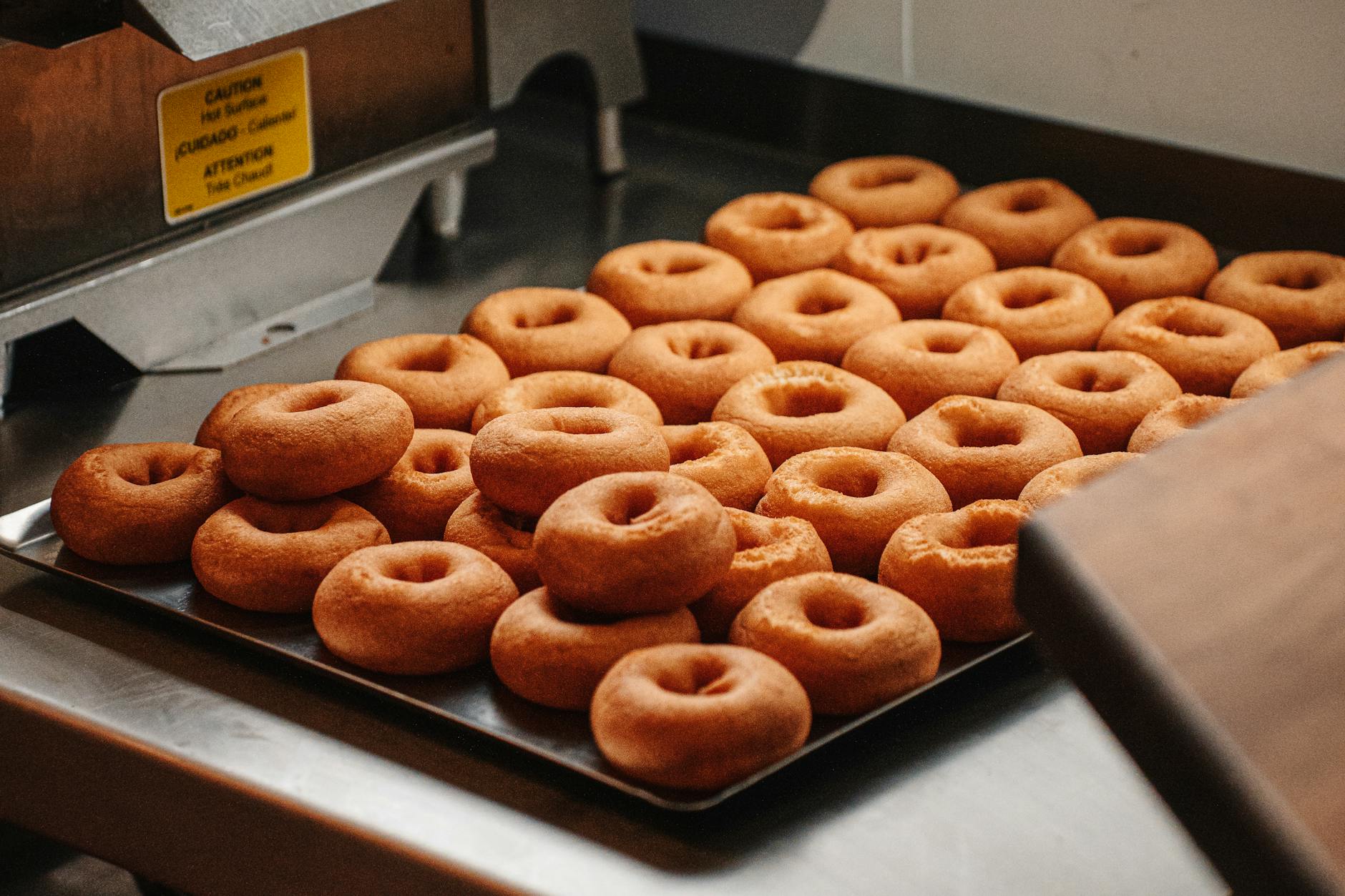 Blacha z pieczonymi pączkami studzącymi się w kuchni cukierni