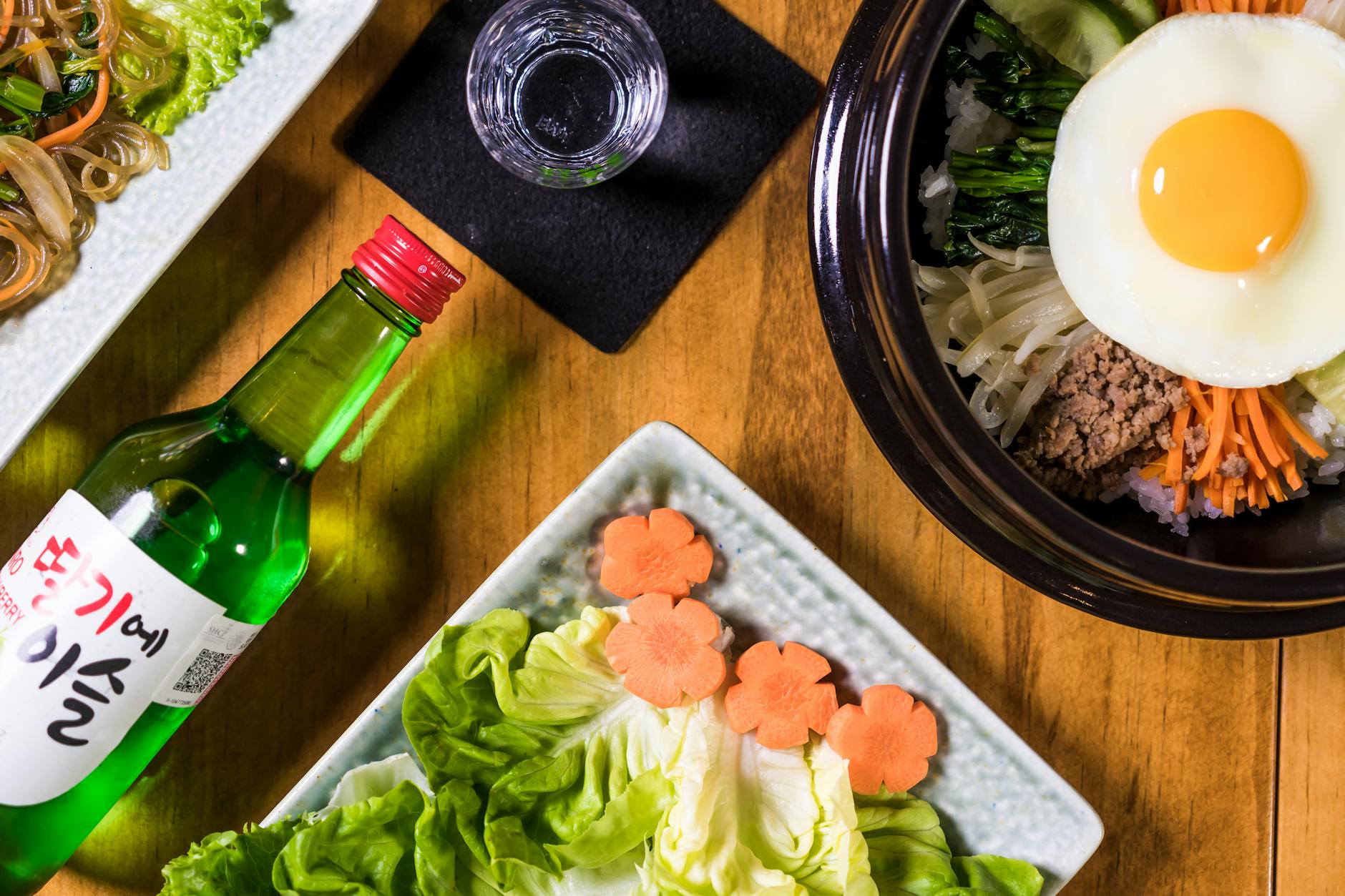 Koreański bibimbap z kolorowymi dodatkami i kieliszkiem soju