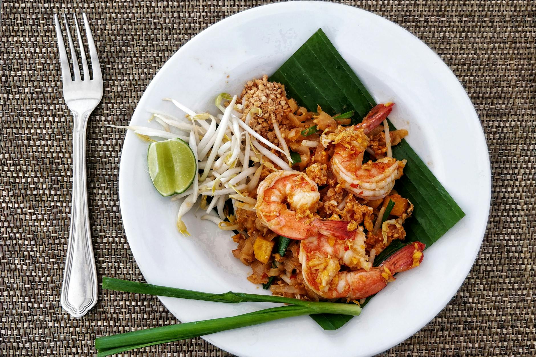 Pad thai z krewetkami na liściu bananowca, podany z limonką