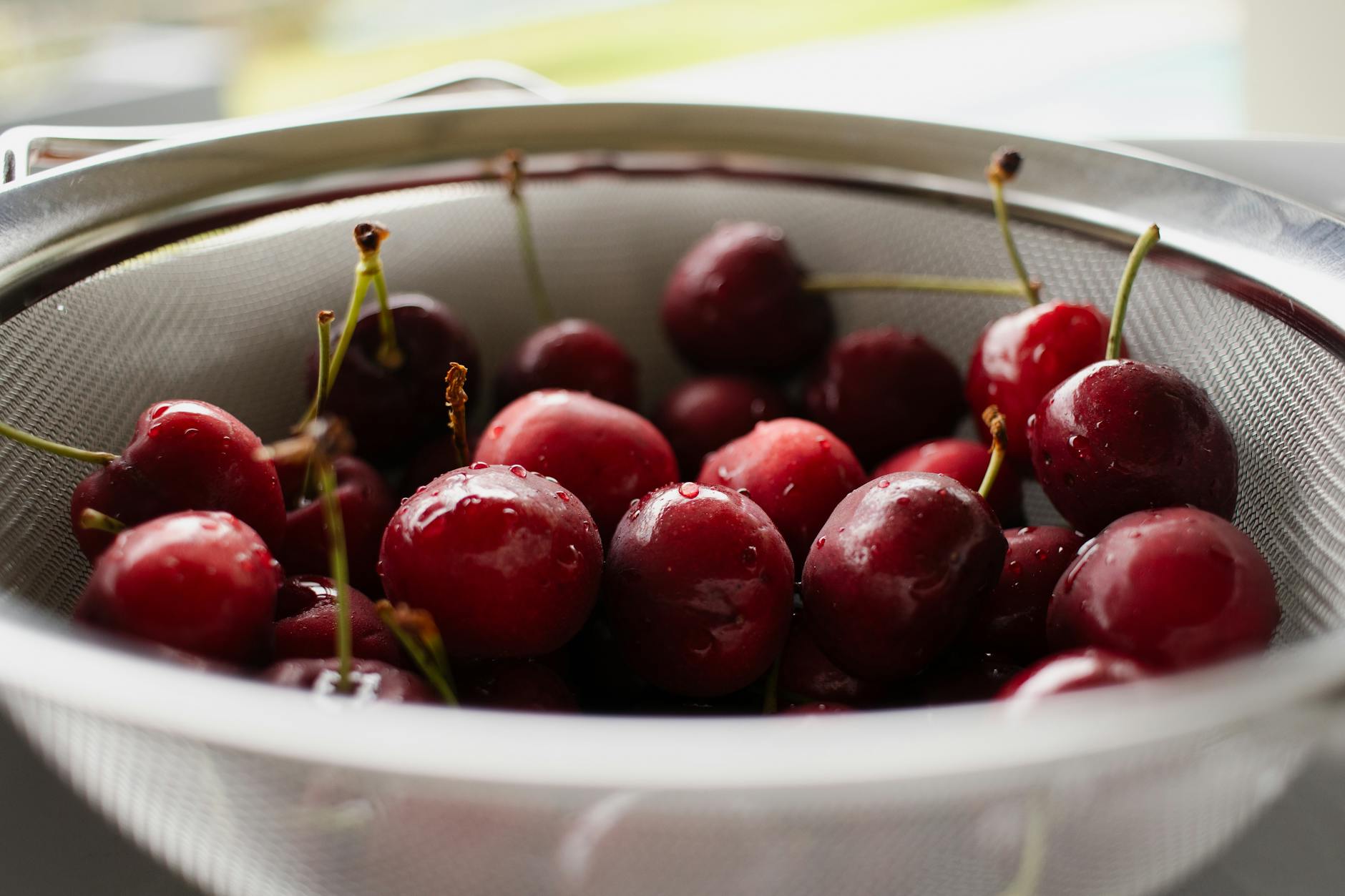 Świeże mokre czereśnie w metalowym durszlaku w kuchni
