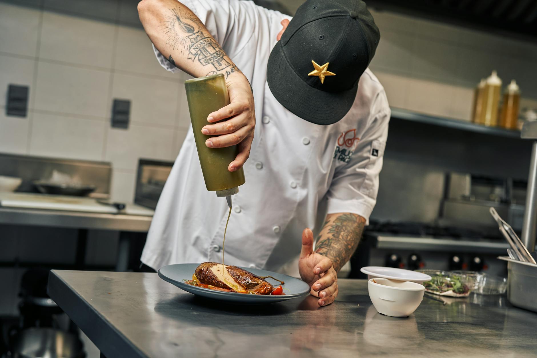 Szef kuchni polewa danie sosem w profesjonalnej kuchni