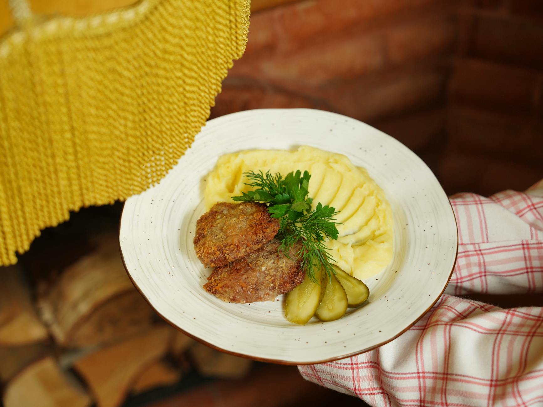 Szwedzkie klopsiki z sosem, puree ziemniaczanym i ogórkami na talerzu