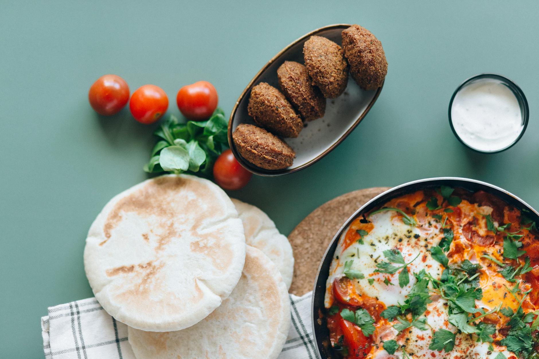 Szakszuka, falafel i pita na zielonym stole w stylu bliskowschodnim