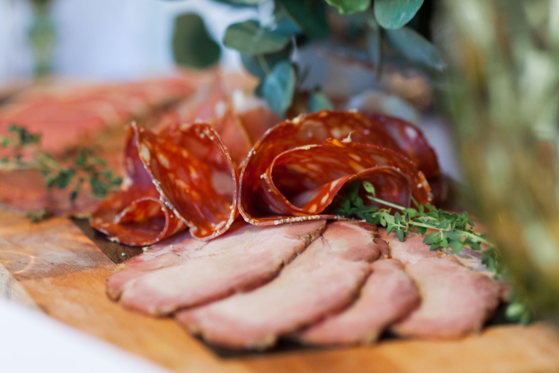 Cienkie plastry salami i wędzonego mięsa na drewnianym stole