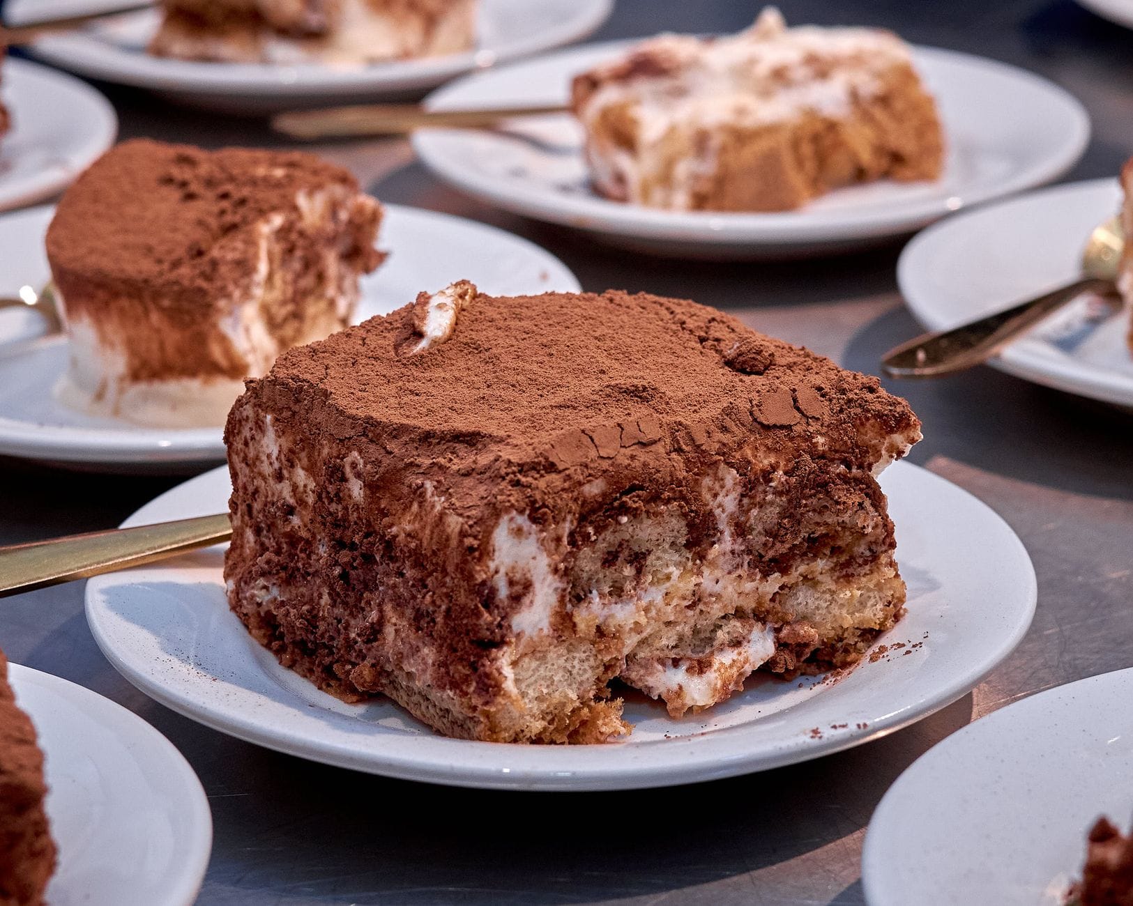 Porcja tiramisu na białym talerzu, posypana kakao