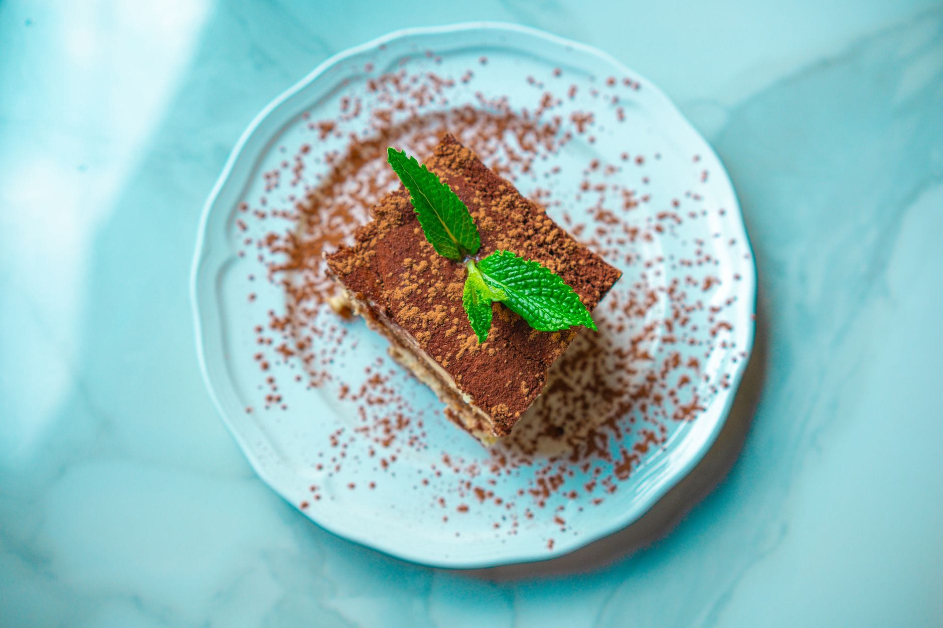 Porcja tiramisu z listkiem mięty na marmurowym talerzu